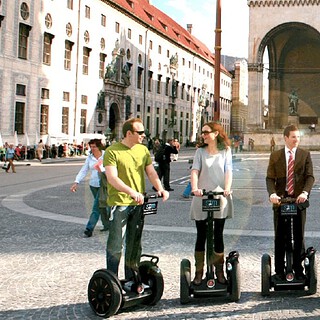 Fünf Menschen stehen mit Segways auf einem Platz