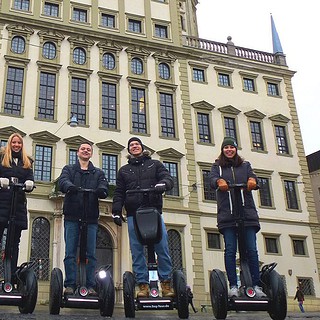 Personen stehen auf den Segway vor einem Gebäude in Augsburg