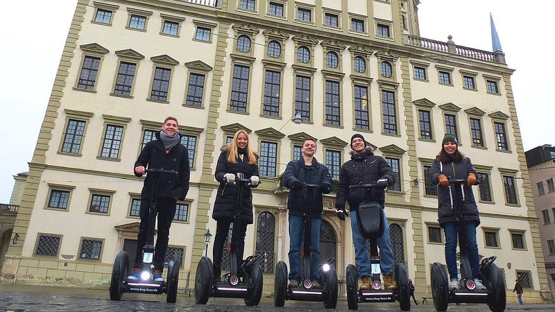 Personen stehen auf den Segway vor einem Gebäude in Augsburg