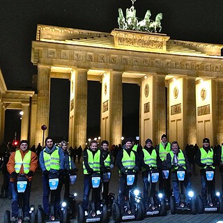 Segways stehen nachts mit Personen vor dem Brandenburger Tor