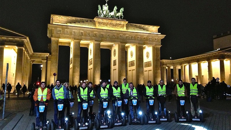 Segways stehen nachts mit Personen vor dem Brandenburger Tor