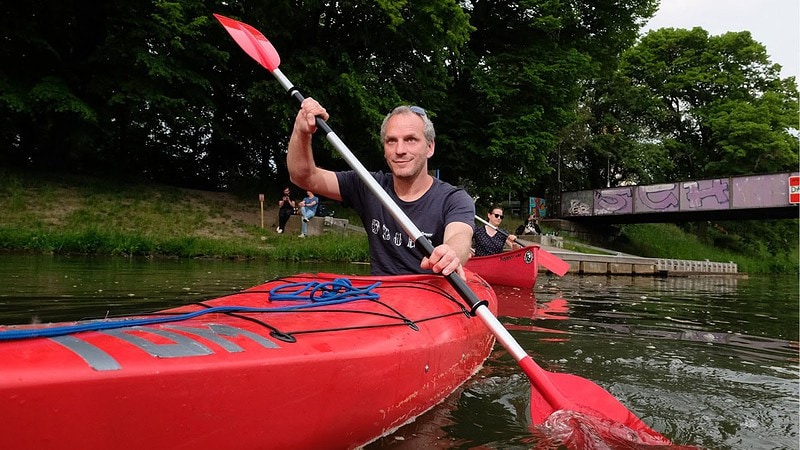 Mann im roten Kajak fährt den Fluss entlang