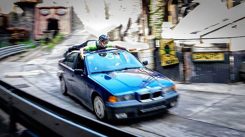 Stuntman fährt mit Helm auf dem Dach eines BMWs