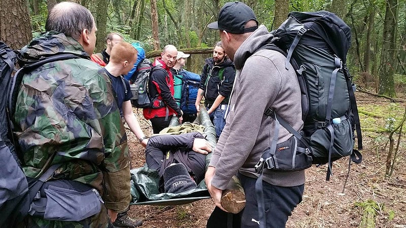 Team im Wald mit verletzter Person im auf einer Trage.