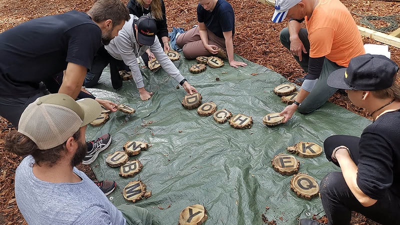 Gruppe beim Buchstabenrätsel auf einer Plane