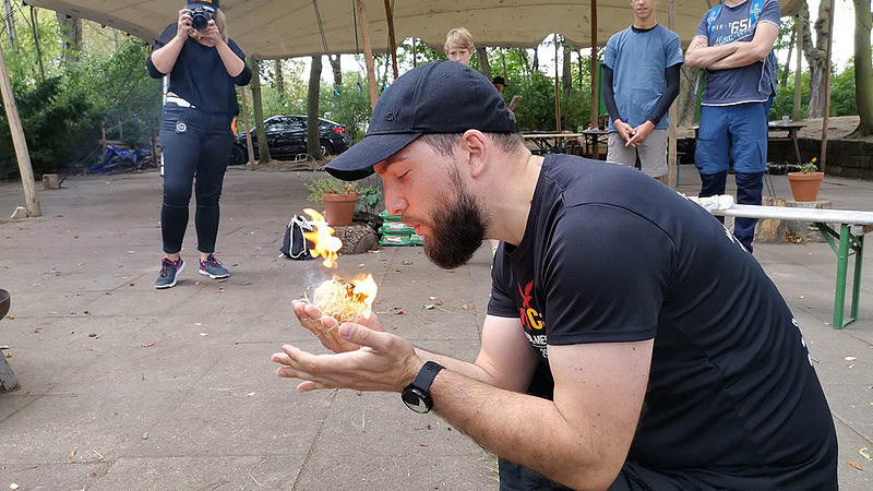 Mann mit brennender Holzwolle in den Händen.