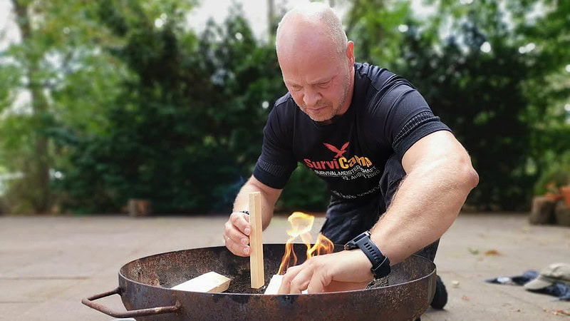 Mann beim Feuermachen in Feuerschale.