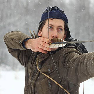 Mann im Winter beim Bogenschießen im Schnee.