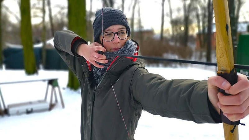 Frau beim Bogen spannen und Zielen.