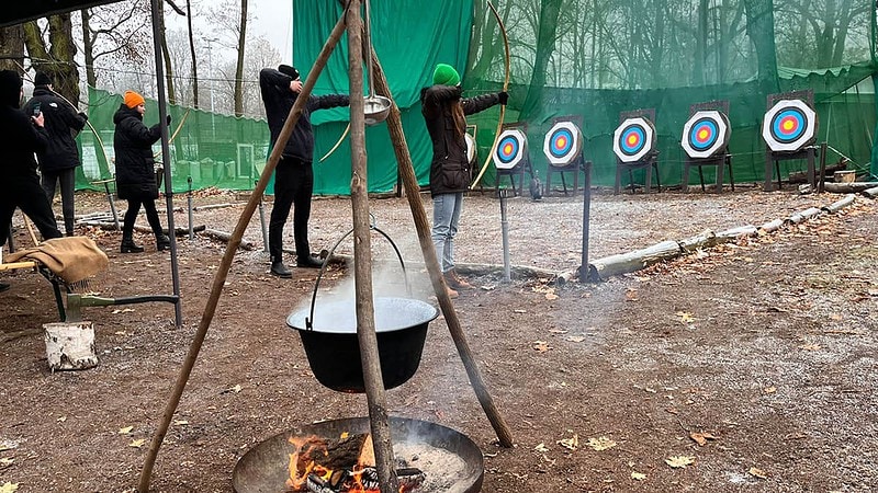 Bogenschießen mit Feuerschale im Vordergrund.