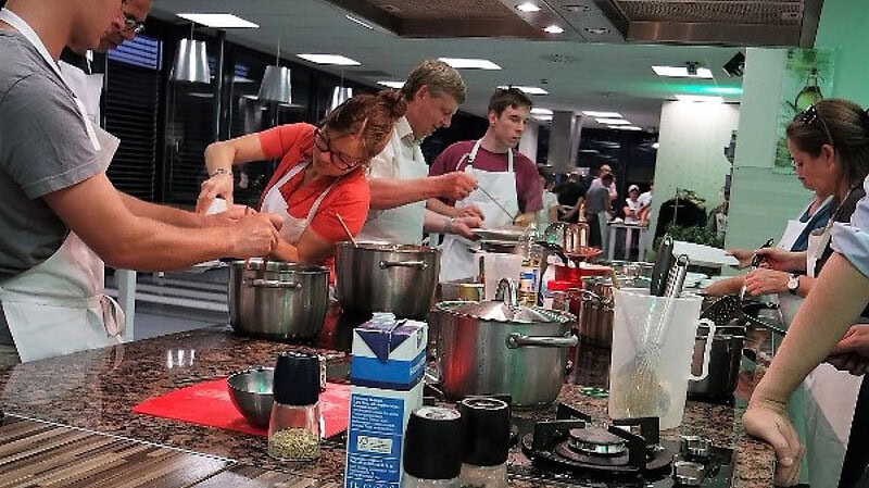 Gruppe kocht in offener Küche beim Teamkochen in Dresden