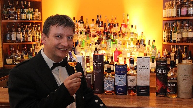 Mann verkostet Whisky und Bar im Hintergrund beim Whisky Tasting in Flöha