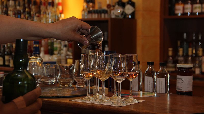 Meßbecher gießt Whisky in Gläser zum Tasting in Flöha