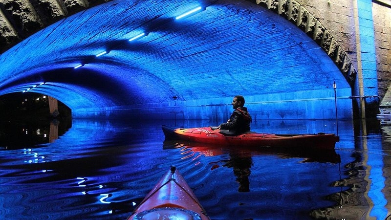 Kajak unter Brücke bei Nacht