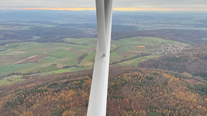 Ausblick aus dem Seitenfenster der Cessna mit Blick über Felder und Wälder