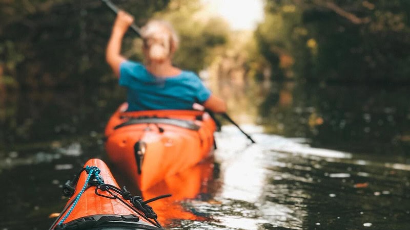 Frau im Kajak fährt durch ein Kanal