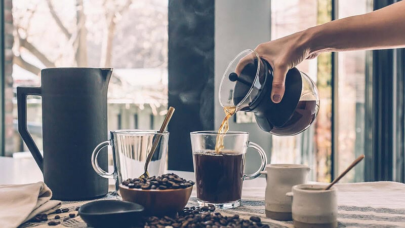 Eine Person gießt frisch gekochten Kaffee in eine Tasse ein.