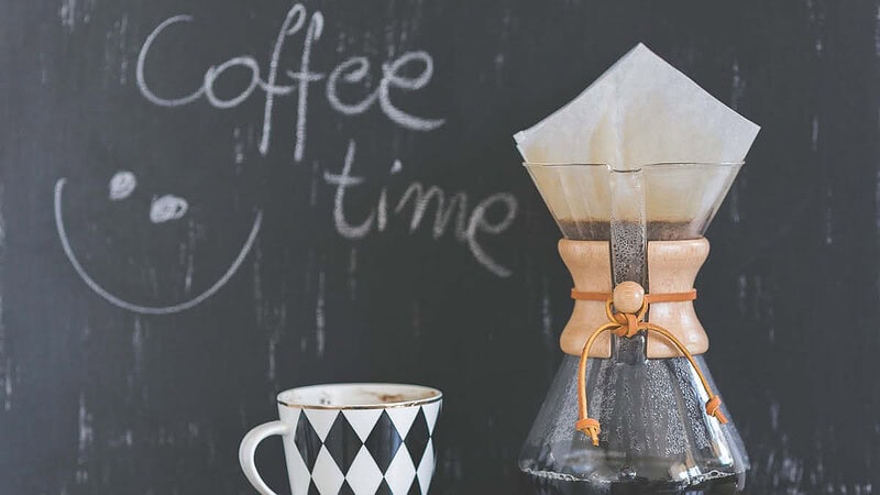 Ein frisch gemachte Kaffeekanne steht vor einer Tafel.