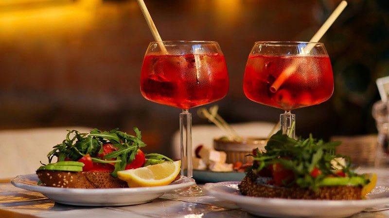 2 Gläser Aperol Spritz auf einem Tisch in einem Restaurant, neben dem Essen