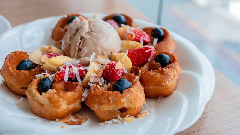 Buntes Dessert, serviert auf einem Teller mit einer Kugel Eis und Obst