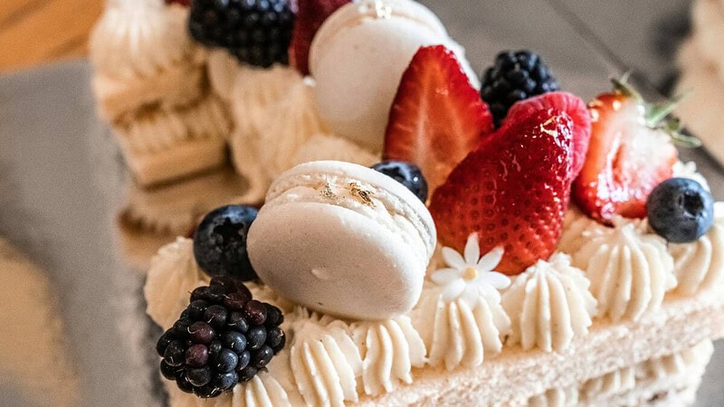 Kuchen mit weißer Schokolade, dekoriert mit Früchten und Macarons