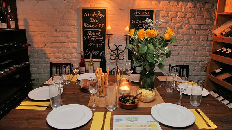 Gedeckter Tisch mit Blumen, einer Kerze und beilagen zum Wein, in einem gemütlichen Wein Lokal