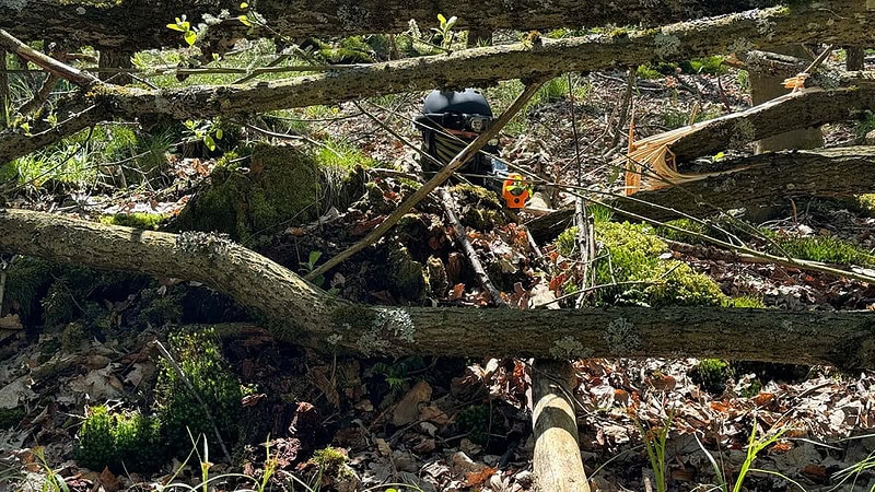 Ein Lasertag Spieler der zwischen Ästen versteckt ist.