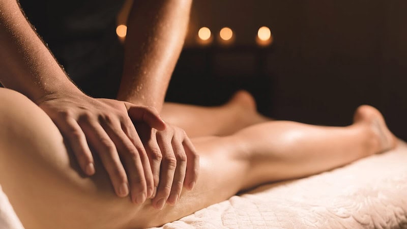 Ein Mann massiert die Beine seiner Frau und nutzt verschiedene Massagetechniken