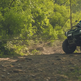 Zwei Quadfahrer im Wald auf einem Schotterweg