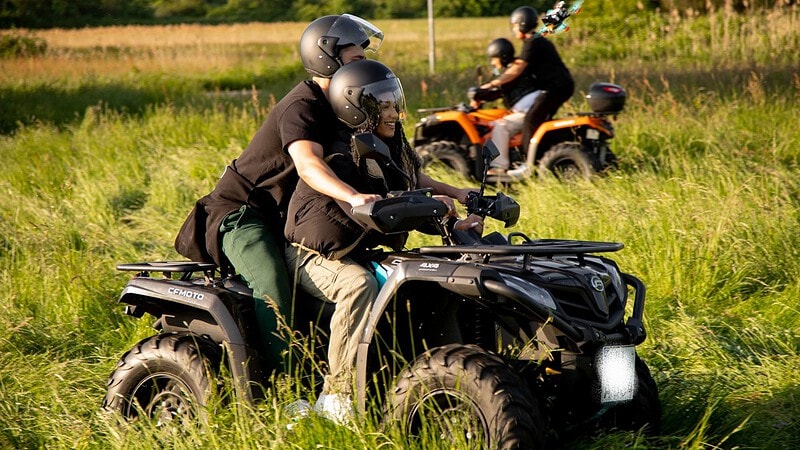 Erwachsener mit Kind auf einem schwarzen Qaud beim fahren