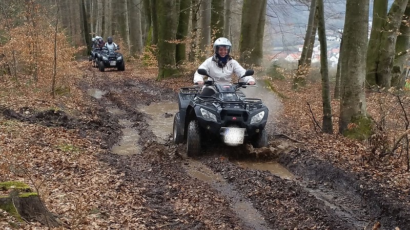 Eine Frau fährt mit ihrem Quad durch einen schlammigen Waldweg