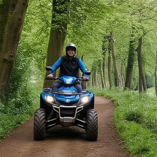 Ein Quadfahrer mit blauem Quad auf Waldweg