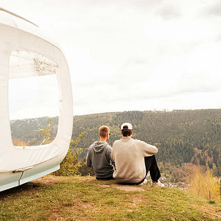 1 Personen sitzen vor dem Cube und schauen sich die Natur und Wälder an