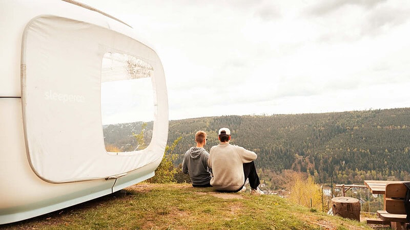 1 Personen sitzen vor dem Cube und schauen sich die Natur und Wälder an