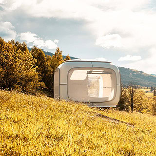 Aussicht auf den Sleep Cube und die Alpen von einem Hügel aus.