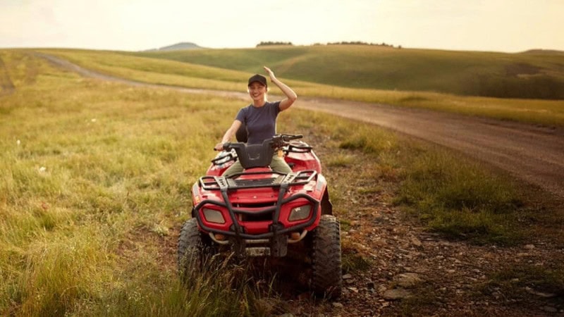 Frau die neben einem Feldweg auf einem Quad sitzt.