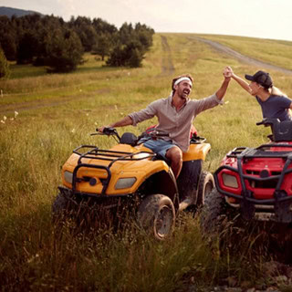 Ein Paar auf 2 Quads welches die Hände freudig hält und sich an lacht.