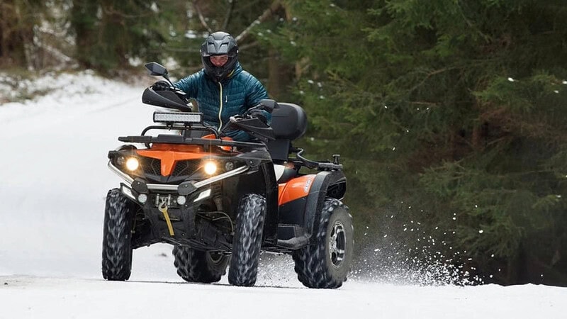 Ein Quad Fahrer der auf Schnee Driftet.