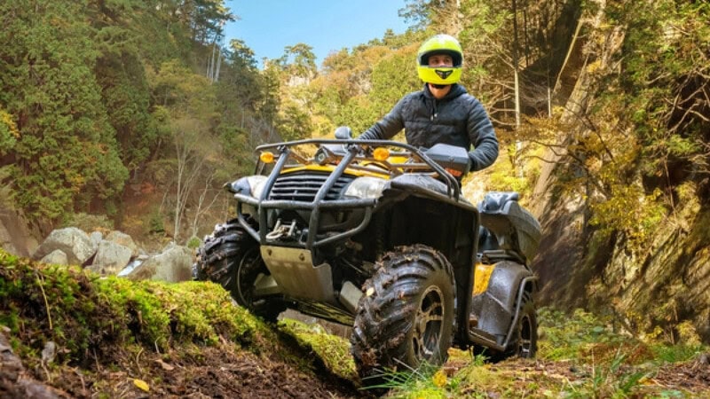 Ein Quad Fahrer der in einem Tal über einen Hügel fährt.