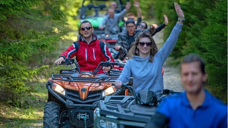 Eine Gruppe von Quadfahrern die hintereinander fahren und in die Kamera winken.